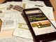 Smartphone exibe site da Coelba ao lado de contas de energia elétrica com caneta sobre mesa