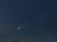 Imagem noturna de um cometa semelhante ao Cometa do Diabo, brilhante atravessando o céu estrelado, visível acima do horizonte.
