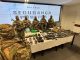 Membros armados da segurança pública em frente a uma mesa exibindo armas apreendidas durante operações do primeiro trimestre de 2024 em coletiva de imprensa em Salvador, Bahia