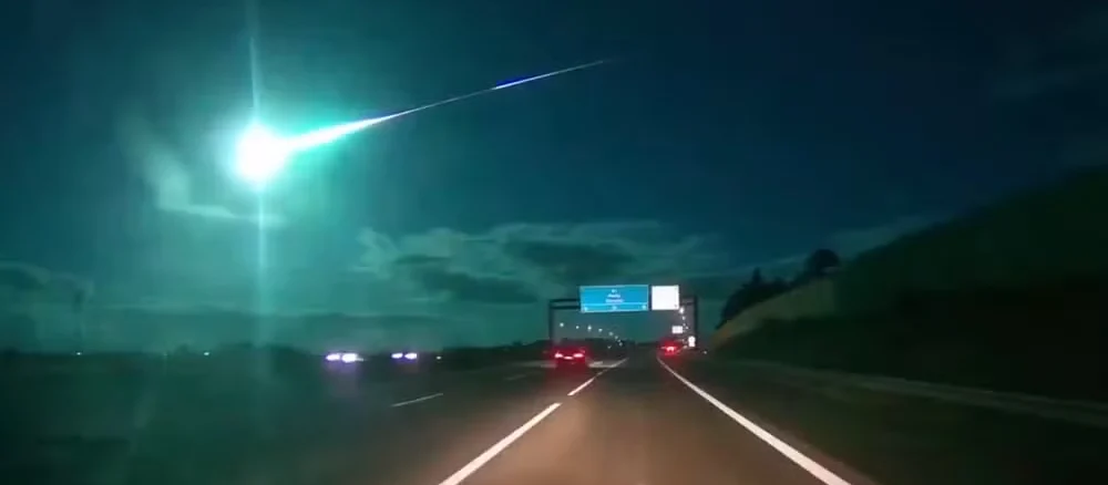 Um meteoro azul brilhante cruzando o céu noturno sobre uma estrada em Portugal e Espanha.