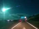 Um meteoro azul brilhante cruzando o céu noturno sobre uma estrada em Portugal e Espanha.