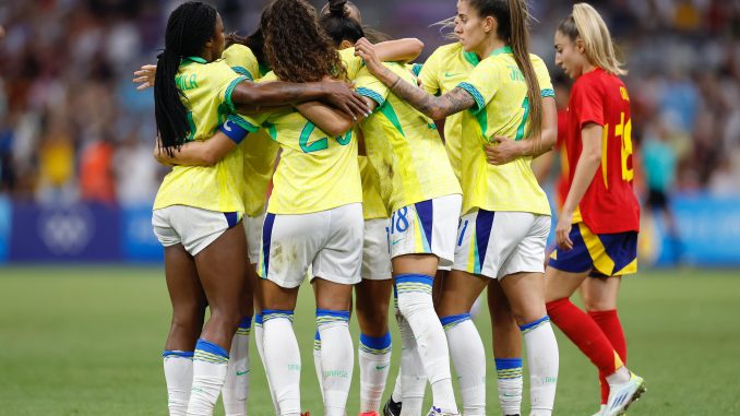 Jogadoras da seleção feminina de futebol do Brasil se abraçam em comemoração durante a partida contra a Espanha nas Olimpíadas de Paris 2024.