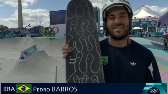 Pedro Barros, skatista brasileiro, sorri segurando seu skate durante Olimpíadas de Paris, com o ranking mundial e idade exibidos na tela.