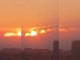 Imagem de um pôr do sol em Chengdu, China, onde a refração e reflexão da luz em camadas de vidro criam a ilusão de sete sóis no céu.